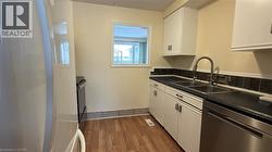 Kitchen with stainless steel appliances, dark countertops, white cabinets, and dark wood-type flooring - 