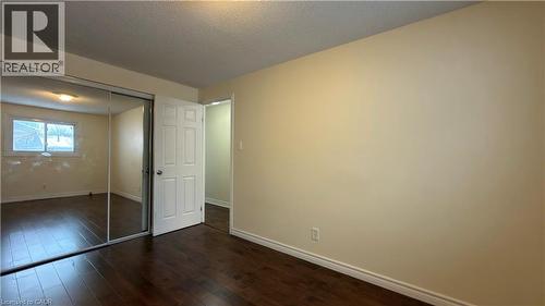 Unfurnished bedroom with dark wood-style floors, a closet, and a textured ceiling - 66 Glamis Road Unit# 33, Cambridge, ON - Indoor Photo Showing Other Room