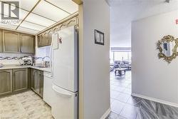 Kitchen with light tile patterned floors, white appliances, a sink, light countertops, and decorative backsplash - 