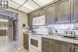 Kitchen with tasteful backsplash, white appliances, and light countertops - 