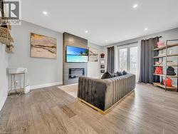 Living room featuring light wood-type flooring, a large fireplace, and recessed lighting - 
