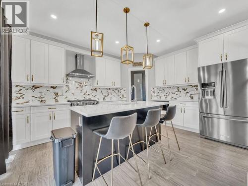 Kitchen with high quality fridge, white cabinetry, decorative light fixtures, an island with sink, and recessed lighting - 3374 Oriole Drive, London, ON - Indoor Photo Showing Kitchen With Upgraded Kitchen