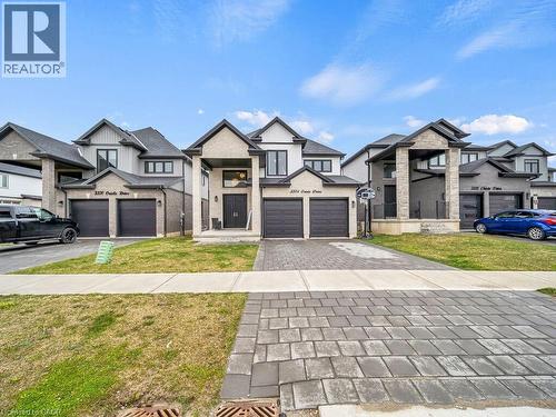 View of front of property with a front lawn, a residential view, decorative driveway, a garage, and board and batten siding - 3374 Oriole Drive, London, ON - Outdoor With Facade