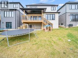 Back of property featuring a trampoline, stairs, and a yard - 