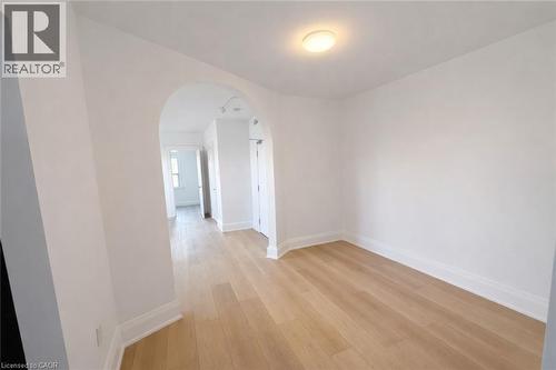 Empty room with arched walkways and light wood-style floors - 17 Louisa Street, Kitchener, ON - Indoor Photo Showing Other Room