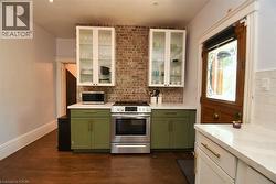 Kitchen featuring white cabinetry, green cabinetry, appliances with stainless steel finishes, and dark wood-style floors - 