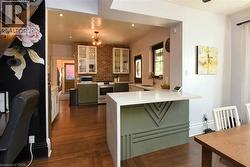 Kitchen featuring green cabinetry, a peninsula, stainless steel appliances, dark wood finished floors, and recessed lighting - 