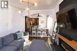 Living area featuring arched walkways, dark wood-style floors, a ceiling fan, and a fireplace - 