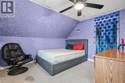 Carpeted bedroom featuring ceiling fan and vaulted ceiling - 
