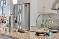 Kitchen view of under cabinet range hood, appliances with stainless steel finishes, light stone counters, and white cabinets - 