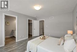 Bedroom featuring a spacious closet, ensuite bath, and light wood-style floors - 