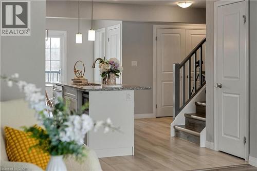 Kitchen with pendant lighting, light stone counters, light wood-type flooring, and a kitchen island with sink - 492 Wismer Street, Waterloo, ON - Indoor