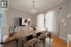 Dining area featuring ornate columns, a raised ceiling, wood finished floors, and baseboards - 