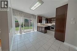Kitchen featuring stainless steel gas range oven, under cabinet range hood, light countertops, and light tile patterned floors - 