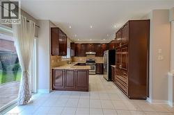 Kitchen featuring stainless steel appliances, a sink, light tile patterned flooring, under cabinet range hood, and backsplash - 