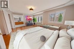 Bedroom with light wood finished floors, a tray ceiling, and ensuite bathroom - 