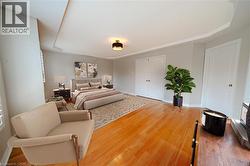 Bedroom with a raised ceiling, light wood-style floors, and baseboards - 