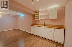 Indoor wet bar with light wood-style floors, baseboards, and tasteful backsplash - 