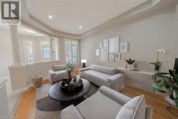 Living room featuring ornate columns, light wood-style floors, a raised ceiling, recessed lighting, and baseboards - 