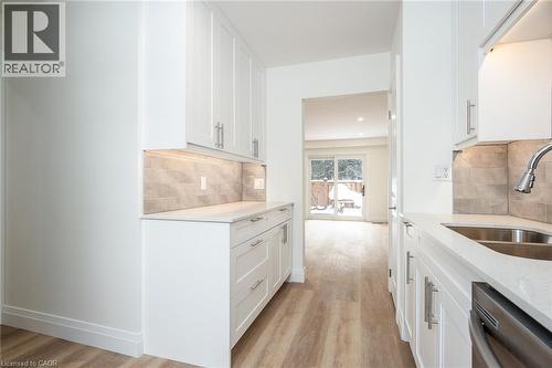 Kitchen featuring light stone counters, white cabinetry, dishwasher, and light wood-style floors - 27 Queenston Drive, Kitchener, ON - Indoor Photo Showing Kitchen With Double Sink