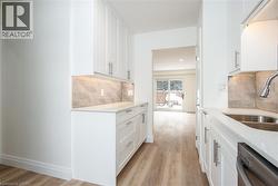 Kitchen featuring light stone counters, white cabinetry, dishwasher, and light wood-style floors - 