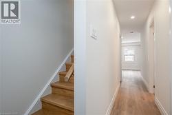 Hall with light wood finished floors, stairway, and recessed lighting - 