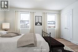 Bedroom featuring wood finished floors, multiple windows, and a closet - 
