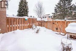 Yard layered in snow featuring a fenced backyard and a gate - 
