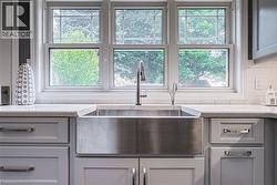 Kitchen with gray cabinetry, light stone counters, and healthy amount of natural light - 