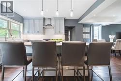 Kitchen with wall chimney range hood, pendant lighting, recessed lighting, dark wood finished floors, and healthy amount of natural light - 