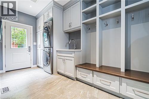 Laundry room featuring stacked washer / drying machine, cabinet space, and light marble finish floors - 25 Orchard Hill, Hamilton, ON - Indoor Photo Showing Laundry Room