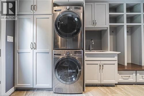 Laundry area with estacked washer and dryer, cabinet space, and light wood finished floors - 25 Orchard Hill, Hamilton, ON - Indoor Photo Showing Laundry Room