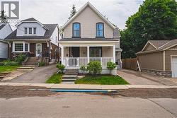 View of front of home with a porch, brick siding, roof with shingles, and asphalt driveway - 