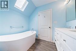 Bathroom with a skylight, vaulted ceiling, a freestanding bath, and double vanity - 