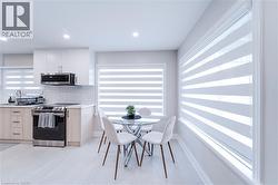 Kitchen with white cabinets, decorative backsplash, light tile patterned floors, light brown cabinetry, and stainless steel appliances - 