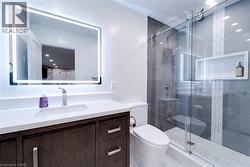 Bathroom featuring a shower with door, vanity, and toilet - 