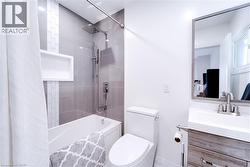 Full bathroom featuring shower / bath combo with shower curtain, vanity, and toilet - 