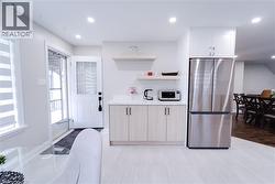 Kitchen with white cabinets, stainless steel fridge, and light hardwood / wood-style floors - 