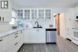 Kitchen with a barn door, white cabinets, glass fronted cabinets, and white appliances - 