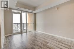 Empty room with floor to ceiling windows, light wood finished floors, and a tray ceiling - 