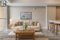 Virtually staged. Living room featuring wood finished floors and a wall of windows - 