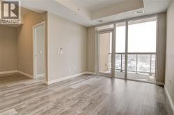 Spare room with floor to ceiling windows, light wood-type flooring, and a raised ceiling - 