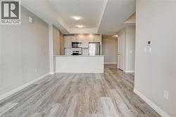 Kitchen with appliances with stainless steel finishes, light wood finished floors, a tray ceiling, light countertops, and a peninsula - 