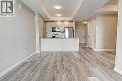 Kitchen with a tray ceiling, stainless steel appliances, light countertops, light wood-type flooring, and open floor plan - 