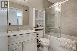Bathroom with enclosed tub / shower combo, vanity, and light tile patterned floors - 
