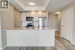 Kitchen with stainless steel appliances, a peninsula, light wood-type flooring, tasteful backsplash, and light stone counters - 