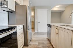 Kitchen featuring stainless steel appliances, light brown cabinetry, light wood-type flooring, and light stone countertops - 