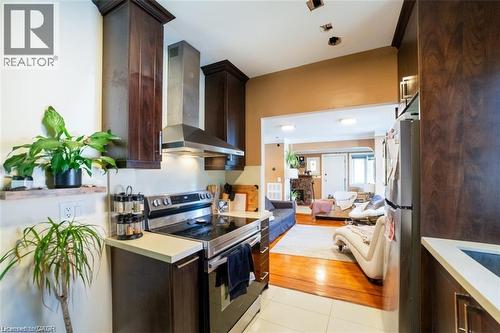 Kitchen with dark brown cabinets, stainless steel appliances, wall chimney range hood, light countertops, and a fireplace - 41 Paradise Road S, Hamilton, ON - Indoor Photo Showing Kitchen With Stainless Steel Kitchen