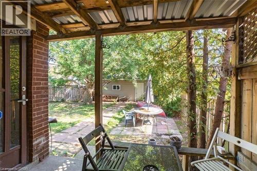 Fenced backyard with outdoor dining area, an outdoor structure, a patio area, and view of scattered trees - 41 Paradise Road S, Hamilton, ON - Outdoor With Deck Patio Veranda With Exterior