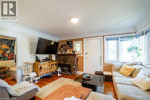 Living area featuring a stone fireplace, wood finished floors, and plenty of natural light - 41 Paradise Road S, Hamilton, ON - Indoor Photo Showing Living Room With Fireplace